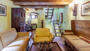 Une pièce chaleureuse avec des poutres en bois, un fauteuil jaune, un canapé et un jeu d’échecs.