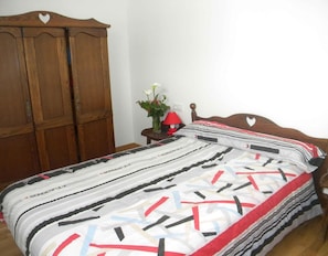A bedroom with a wooden wardrobe, a bedside table with a lamp, and a bed with a striped bedspread. - Apartment 'Ultzama' with Mountain View and Balcony (Iraitzoz)