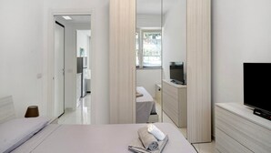 Ein modernes Hotelzimmer mit Bett, Fernseher, Spiegel und Kleiderschrank.