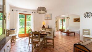 A spacious living area with a dining table, chairs, a lamp, and a globe on the wall.