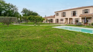 A residential property with a swimming pool, a garden, and a building with a tiled roof.