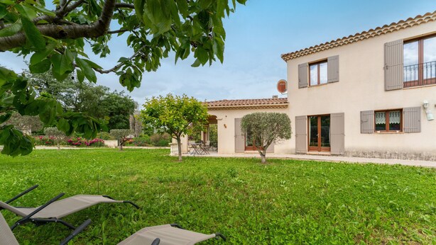 A house with a garden, a patio with chairs, and a satellite dish.