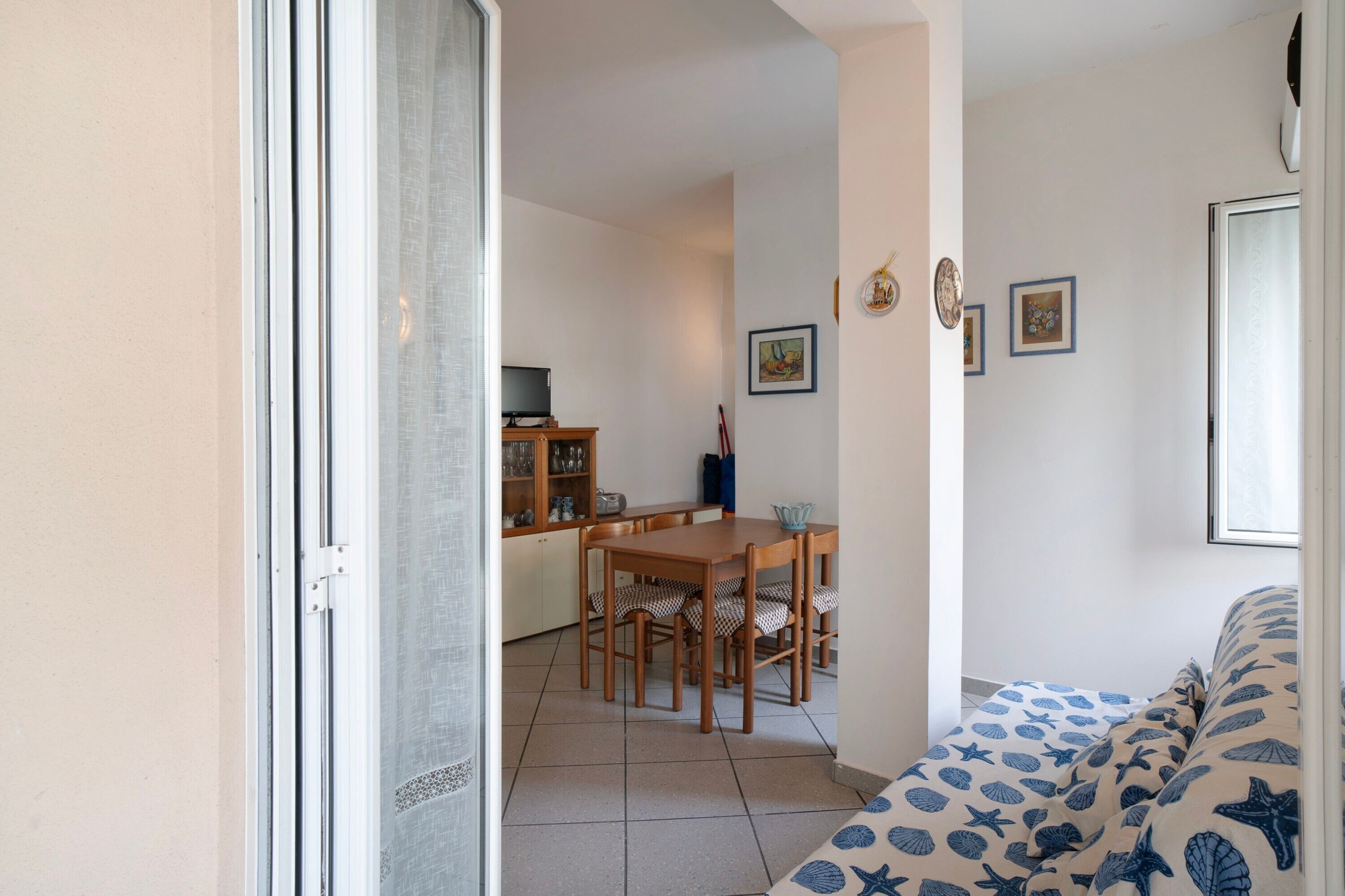 Una stanza con un letto, un tavolo da pranzo con sedie, un angolo cottura e una porta scorrevole in vetro.