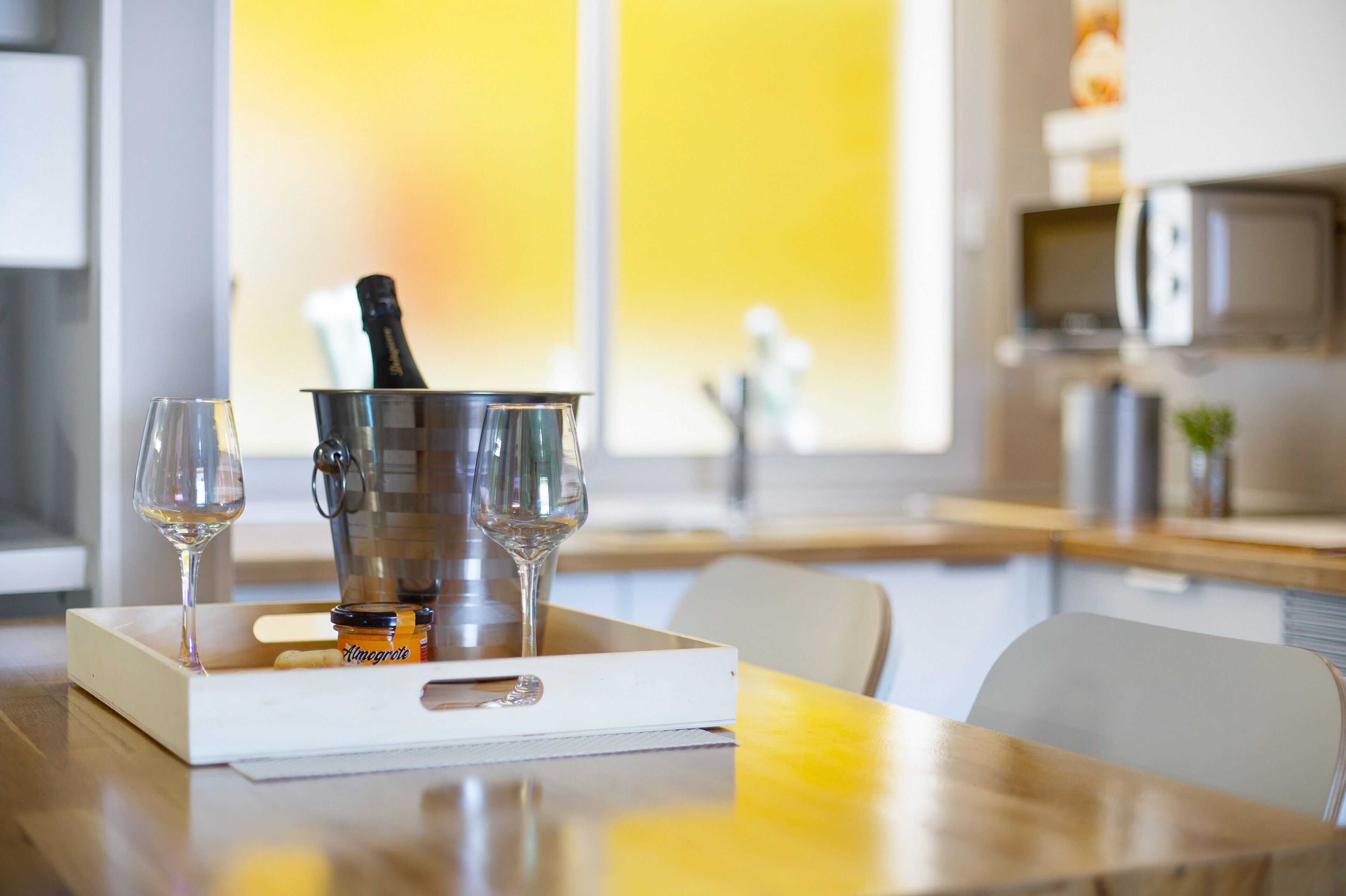 A dining table with a bottle of champagne, two wine glasses, and a white tray.
