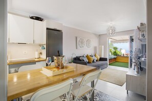 A modern kitchen with a dining area, a sofa with cushions, and a view of the outdoors. - Vacation Apartment 'Casa Ana' with Sea and Teide View, Shared Pool and Wi-Fi (SANTA URSULA)