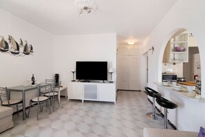 A modern kitchen with a microwave, a dining area with a TV, and a bar area with stools.