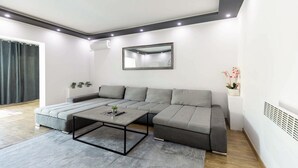 A modern living room with a grey sectional sofa, a coffee table, and a large mirror on the wall.