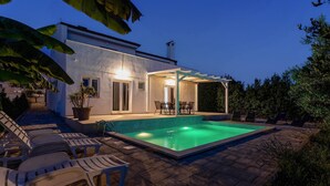 A modern house with a swimming pool, outdoor seating, and a covered patio area.