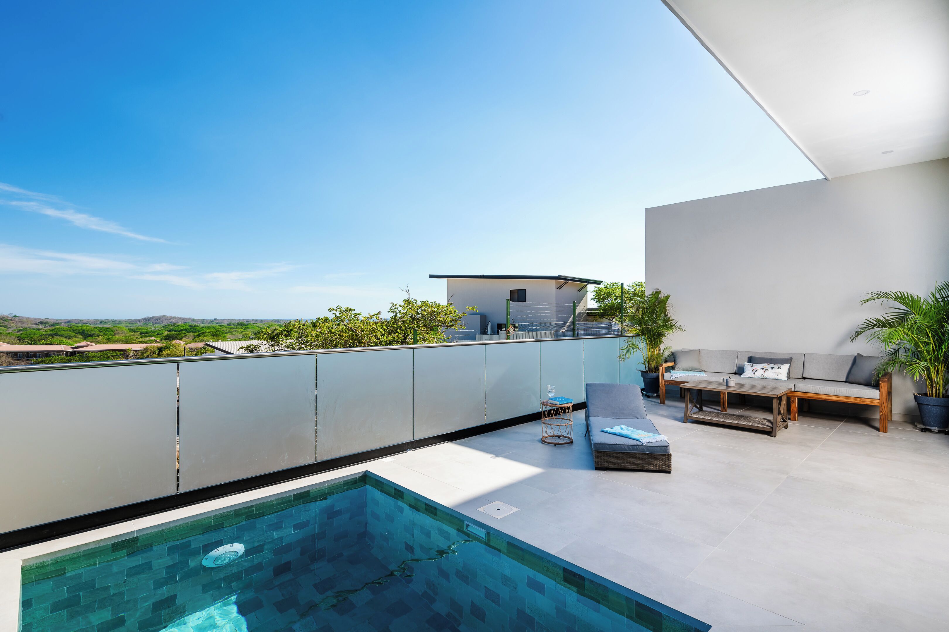 Eine Dachterrasse mit Schwimmbad, einer Sitzecke und Blick auf die Landschaft.