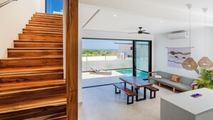Un interior moderno con una escalera de madera, zona de piscina y un área de estar con vistas.