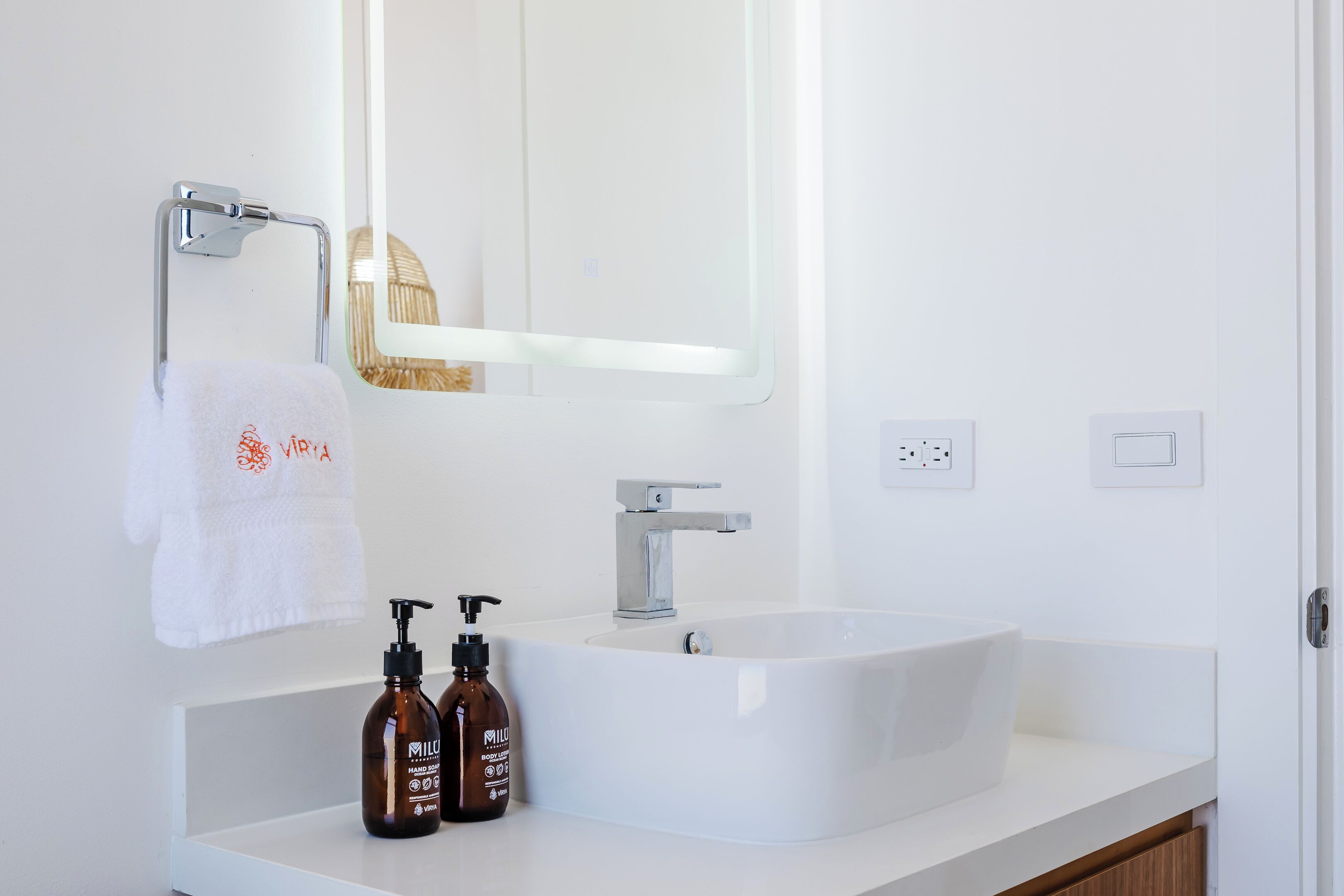 A bathroom with a white sink, a mirror, and two brown bottles of hand soap.