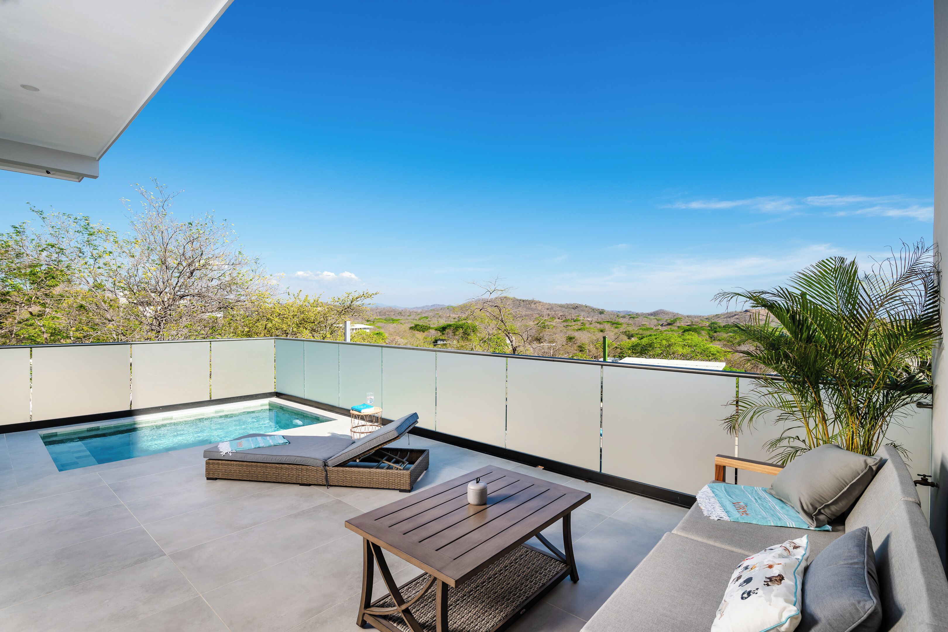 Eine Dachterrasse mit Swimmingpool, Lounge-Bereich und Blick auf die umliegende Landschaft.