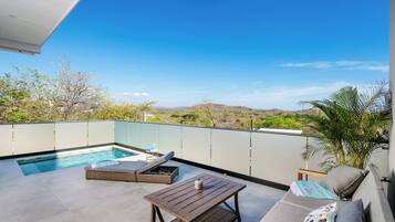 Eine Dachterrasse mit Swimmingpool, Lounge-Bereich und Blick auf die umliegende Landschaft.