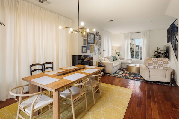Un comedor con mesa y sillas de madera, un sofá y un televisor en una sala de estar.