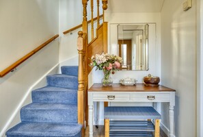 Stunning entryway with a classic staircase, console table, and comfortable bench.