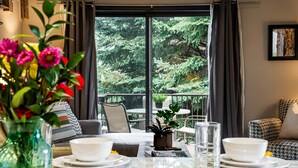 A dining area with a table set for four, a vase with flowers, and a view of a balcony with greenery. - Remodeled with Community Amenities in the Canyons Village (Park City)