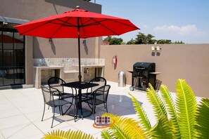 Enjoy al fresco dining and cooking on this outdoor patio with a barbecue grill, table, and comfortable seating for four.