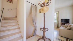 Un escalier menant à un palier, un lampadaire, un canapé et un téléviseur dans un salon.