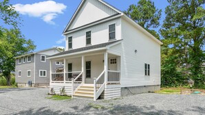 Ein zweistöckiges Haus mit Veranda, überdachter Eingangspforte und Auffahrt.