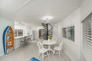 Ein modernes Interieur mit einer weißen Essecke, einer Wendeltreppe und einem Holzboden mit Dekoration.