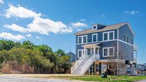 A two-story house with a balcony and a staircase leading to the second floor. - Anchor's Away | Captain's Cove Waterfront w/ Pool & Golf, Pet Friendly + First-Floor Suite (Greenbackville)