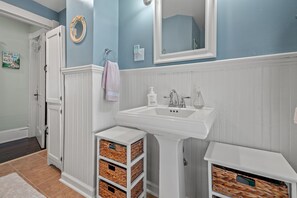 A bathroom with a white sink, a mirror, and storage baskets. - Shore Reflections | Restored Victorian Retreat Near Cape Charles, Spacious & Charming (Cape Charles)