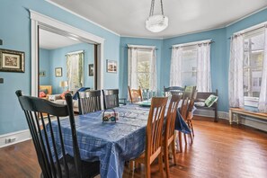 A dining room with a blue tablecloth, wooden chairs, and a chandelier. - Shore Reflections | Restored Victorian Retreat Near Cape Charles, Spacious & Charming (Cape Charles)