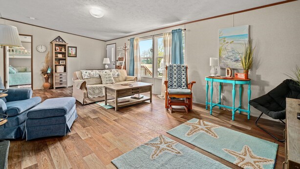 A living room with a sofa, armchairs, a coffee table, and a side table with a lamp.