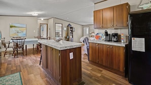 A kitchen with wooden cabinets, a granite countertop, and a black refrigerator.