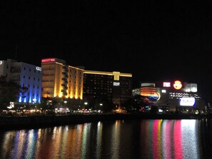 A nighttime cityscape with illuminated buildings, including a hotel with a prominent sign.