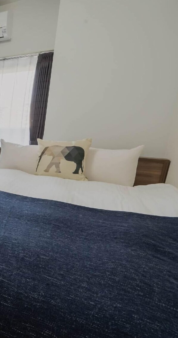 A bed with a dark blue blanket, white pillows, and a wooden headboard.