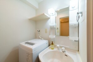 A modern bathroom with a built-in washing machine, a sink, and a mirror.