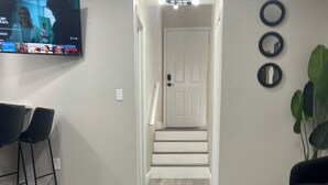 Una sala de estar con una mesa de centro de madera oscura, una alfombra estampada y un televisor montado en la pared.