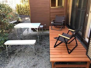 Relax on the outdoor patio with a bench and two chairs, surrounded by lush greenery.