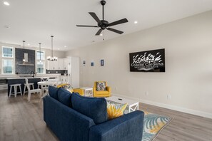 Una sala de estar moderna con un sofá, un sillón amarillo y un comedor, con una cocina al fondo.
