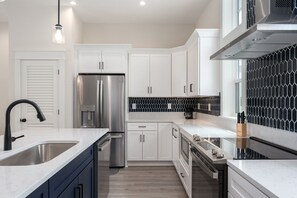 Una cocina moderna con electrodomésticos de acero inoxidable, armarios blancos y un salpicadero blanco y negro.