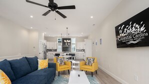 Ein modernes Wohnzimmer mit einer Couch, zwei gelben Sesseln, einem Couchtisch und einem Deckenventilator.