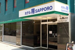 Et hotel med et skilt, der viser 'Hotel Sapporo SAPPORO' og et telefonnummer.