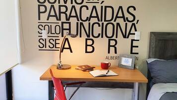 A bedroom with a bed, a desk, and a chair. There is a motivational quote on the wall.