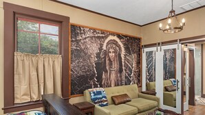 A living room with a sofa, a coffee table, a bench, and a large wall mural.