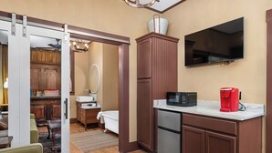A compact kitchen with a microwave, coffee maker, and a TV mounted on the wall.