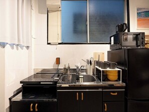 Een koelkast, een magnetron, een kookplaat, kookgerei, borden en bestek