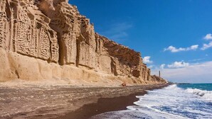Un paisaje costero con una playa arenosa y un acantilado rocoso.