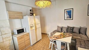 Un espacio habitable compacto con kitchenette, una mesa de comedor y un sofá.