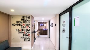 A hotel reception area with a wall displaying multilingual greetings, a reception desk, and a business corner sign. - S09 PREMIUM SUITE Full Service WiFi (Atizapan de Zaragoza)