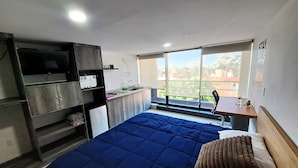 A bedroom with a bed, a desk, a window, and a kitchenette. - S09 PREMIUM SUITE Full Service WiFi (Atizapan de Zaragoza)