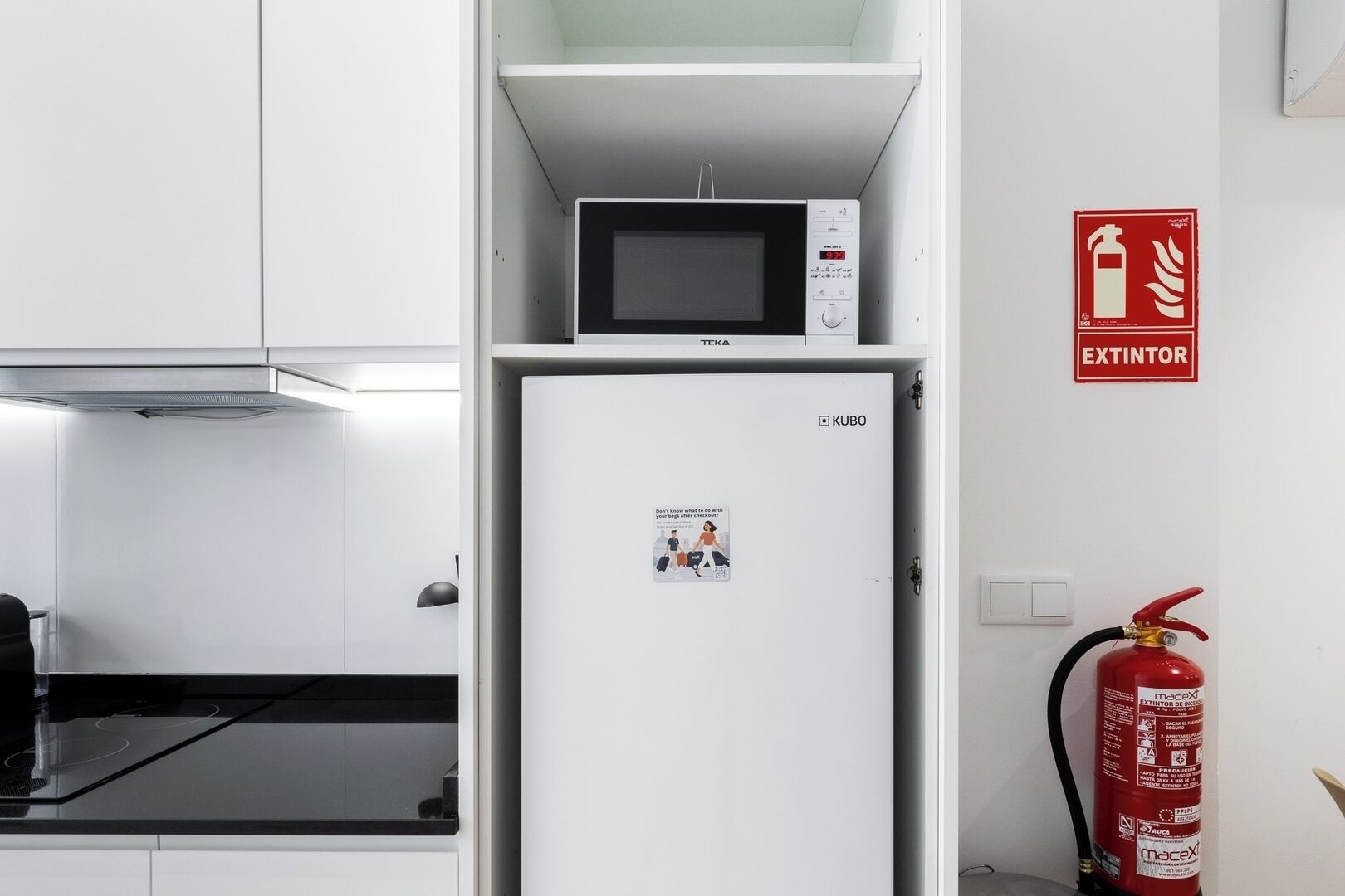 Eine Küche mit Mikrowelle, Kühlschrank und einem an der Wand befestigten Feuerlöscher.