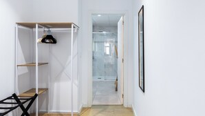 A hallway with a white wardrobe, a wooden bench, and a framed picture on the wall.