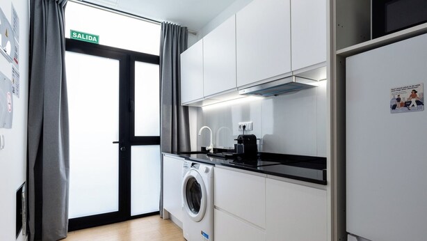 A compact kitchen with a washing machine, a stove, and a refrigerator.