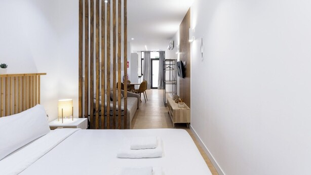 Et moderne hotelværelse med en stor seng, en træskærm, et skrivebord med stol og et fjernsyn.